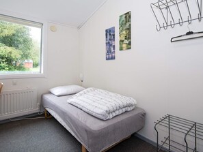 A bedroom with a bed, a radiator, a window, and a wall-mounted drying rack.