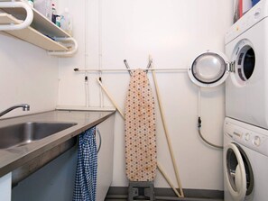 A laundry area with a washing machine, a drying rack, a sink, and a shelf with cleaning supplies. - 20 Person Holiday Home in Herning (Herning)