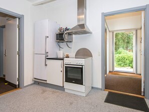 A compact kitchen with a refrigerator, microwave, stove, and a small window.