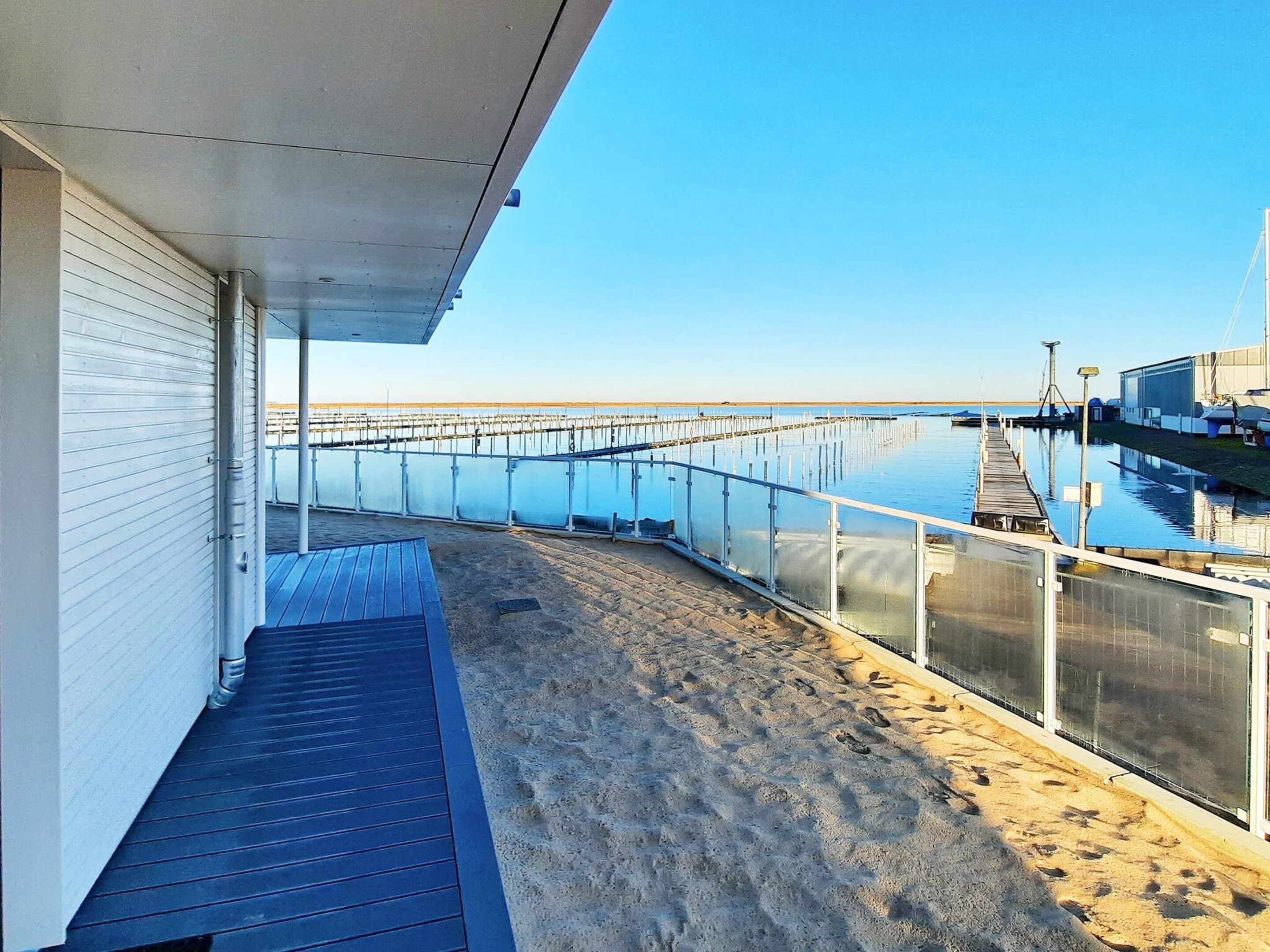 Een balkon aan het strand met uitzicht op het water en een pier.