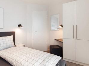 A bedroom with a bed, a wardrobe, a desk, and a mirror. - 5 Star Holiday Home in Wendtorf (Wendtorf)