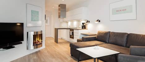 A modern living room with a flat-screen TV, a fireplace, a sofa, and a coffee table.