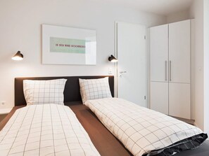 A hotel room with a bed, two bedside lamps, a wardrobe, and a framed picture on the wall. - 5 Star Holiday Home in Wendtorf (Wendtorf)