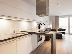 A modern kitchen with a built-in oven, a sink, and a dining area with a sofa and a table. - 5 Star Holiday Home in Wendtorf (Wendtorf)