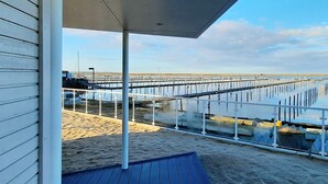 A beachside view with a covered walkway, sandy beach, and a pier extending into the water.