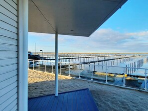 A beachside view with a covered walkway, sandy beach, and a pier extending into the water. - 5 Star Holiday Home in Wendtorf (Wendtorf)
