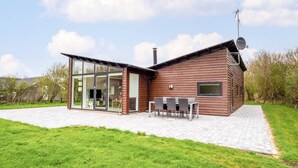 A modern house with a glass extension, a patio with outdoor furniture, and a satellite dish. - 4 Star Holiday Home in Vestervig (Vestervig)