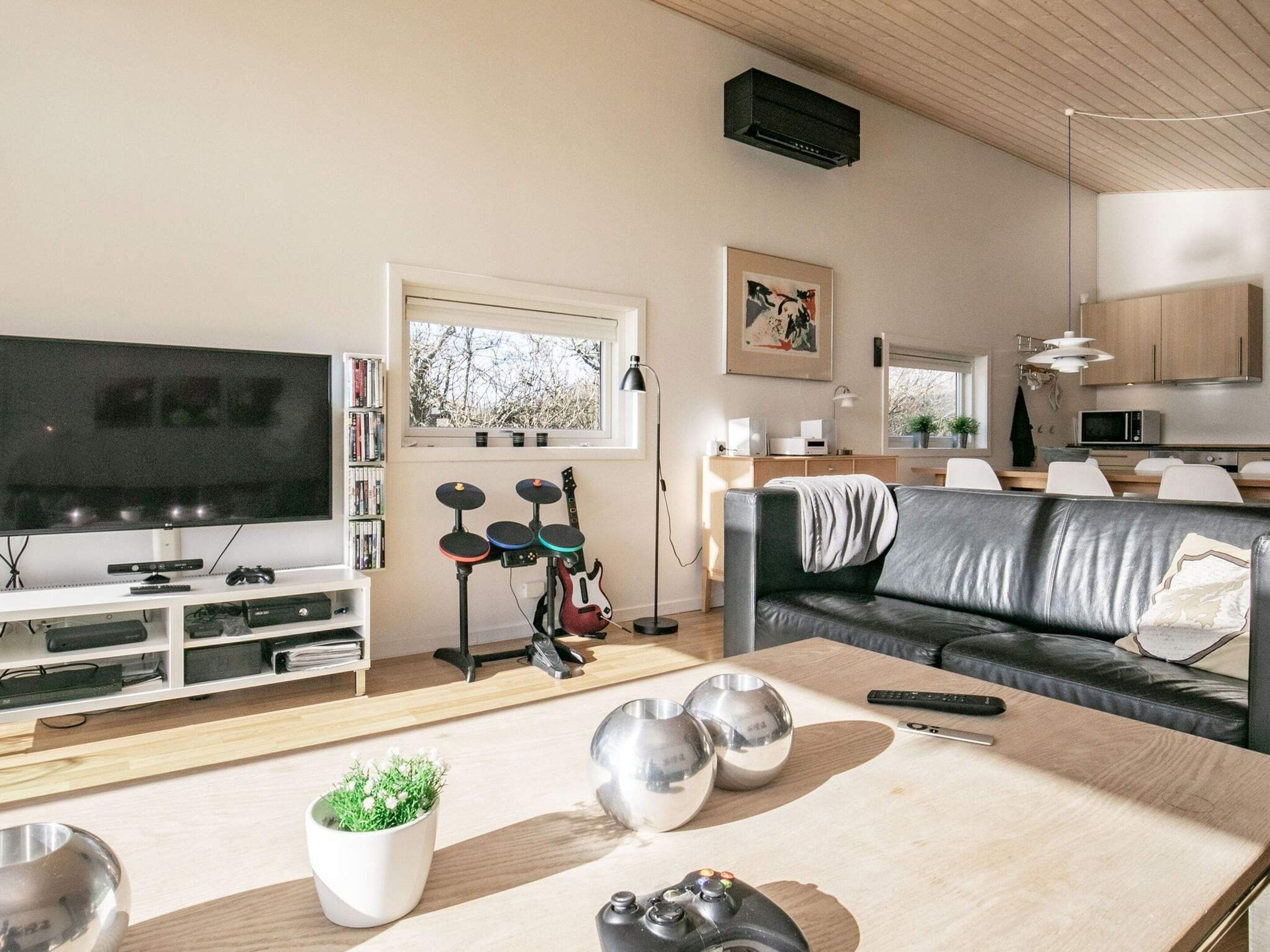 Un salon équipé d’un téléviseur, d’une console de jeux et d’un canapé.