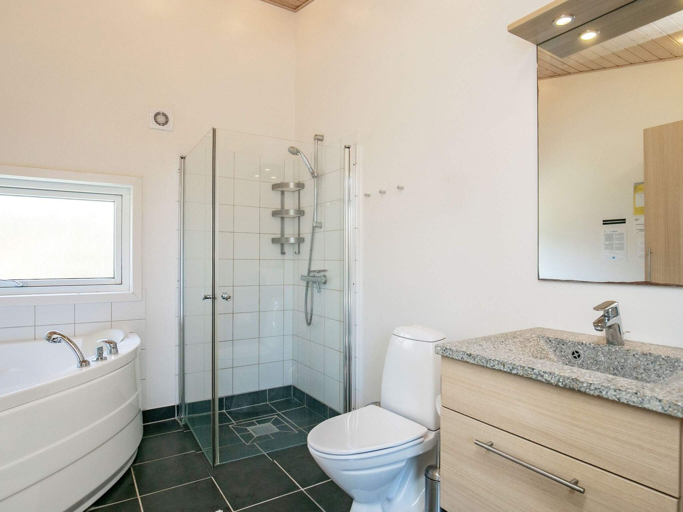 Ein Badezimmer mit einer Duschkabine, einer freistehenden Badewanne, einer Toilette und einem Waschtisch.
