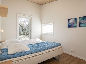 A bedroom with a bed, two windows, and two abstract paintings on the wall. - 4 Star Holiday Home in Vestervig (Vestervig)