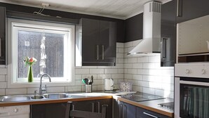 A modern kitchen with dark cabinets, a white countertop, a built-in dishwasher, and a window with a view. - 5 Person Holiday Home in Stromstad (Stromstad)