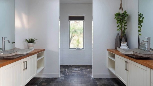 Ein modernes Badezimmer mit zwei Waschbecken, einem Fenster und einer Topfpflanze.