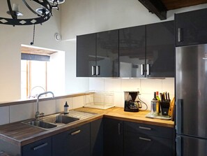Una cocina moderna con armarios negros, electrodomésticos de acero inoxidable y encimera de madera.