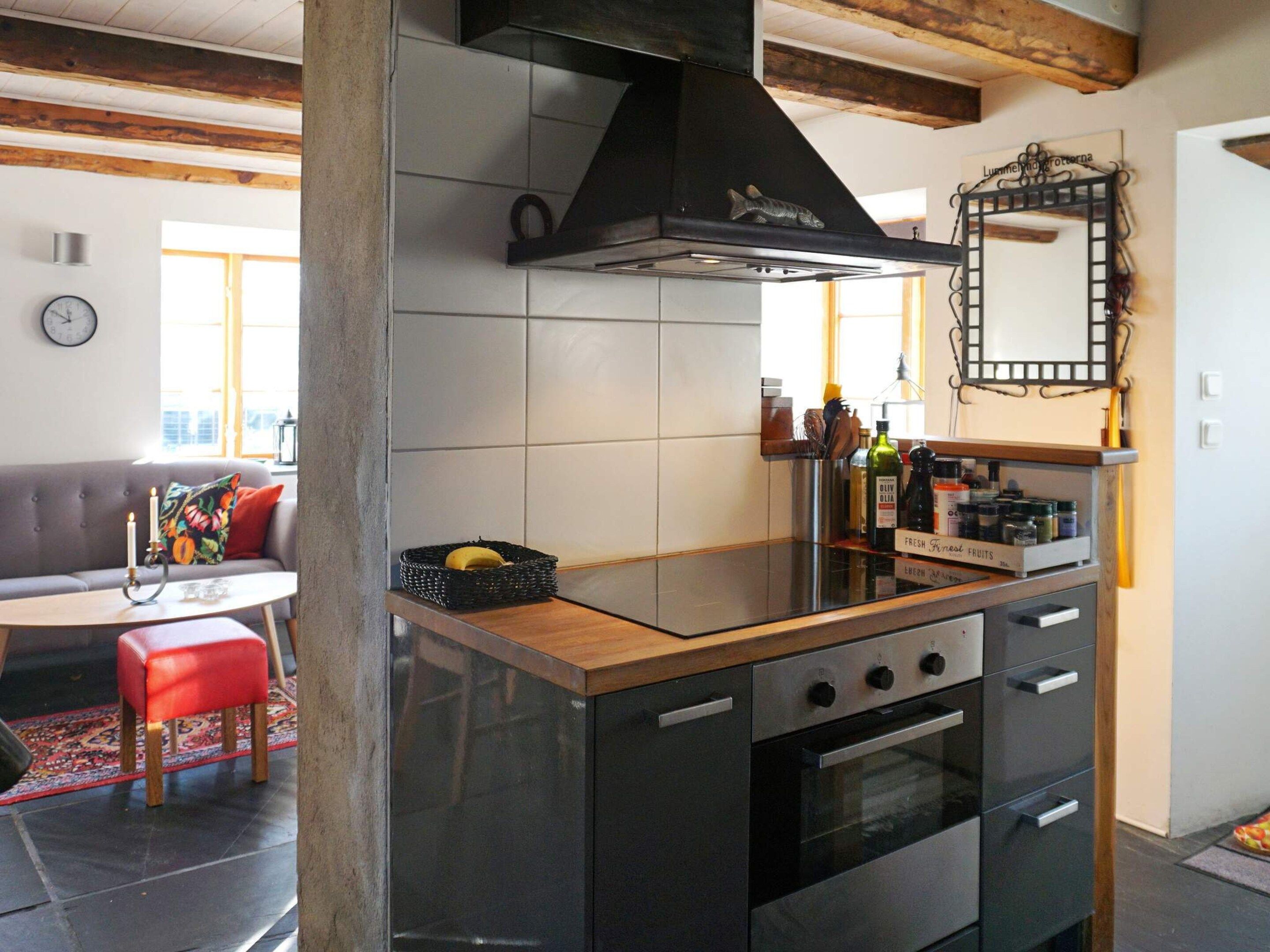 A modern kitchen with a central island, a stove, oven, and a black range hood.
