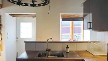 A kitchen with a sink, a window, and a pendant light fixture.