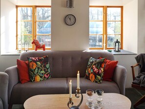 A cozy living room with a grey sofa, colorful cushions, a lit candle, and a clock on the wall. - 4 Star Holiday Home in Slite (Slite)