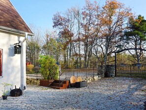 Une maison avec une allée en gravier, un mur en pierre et une clôture en métal.