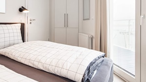 Une chambre d’hôtel avec un lit, une armoire, un radiateur et une fenêtre avec des rideaux.
