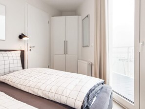 A hotel room with a bed, a wardrobe, a radiator, and a window with curtains.