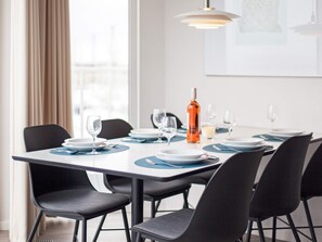 Une table à manger dressée avec des assiettes, des verres et une bouteille, entourée de chaises.