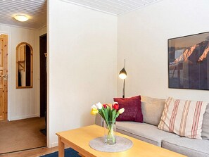 A living room with a wooden table, a vase with flowers, a sofa with cushions, a lamp, and a framed picture on the wall. - 4 Person Holiday Home in Salen (Salen)