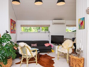 A cozy living room with a sofa, two chairs, a television, and a large plant. - 4 Star Holiday Home in Malling (Malling)