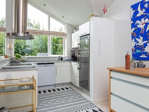 A modern kitchen with a stainless steel refrigerator, a dishwasher, and a window with a view of greenery. - 4 Star Holiday Home in Malling (Malling)