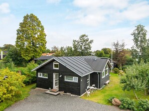 A black house with a sloped roof, surrounded by lush greenery and trees. - 4 Star Holiday Home in Malling (Malling)