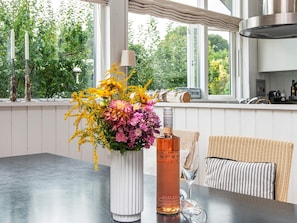 A dining table with a vase of flowers and a bottle of rosé wine. - 4 Star Holiday Home in Malling (Malling)