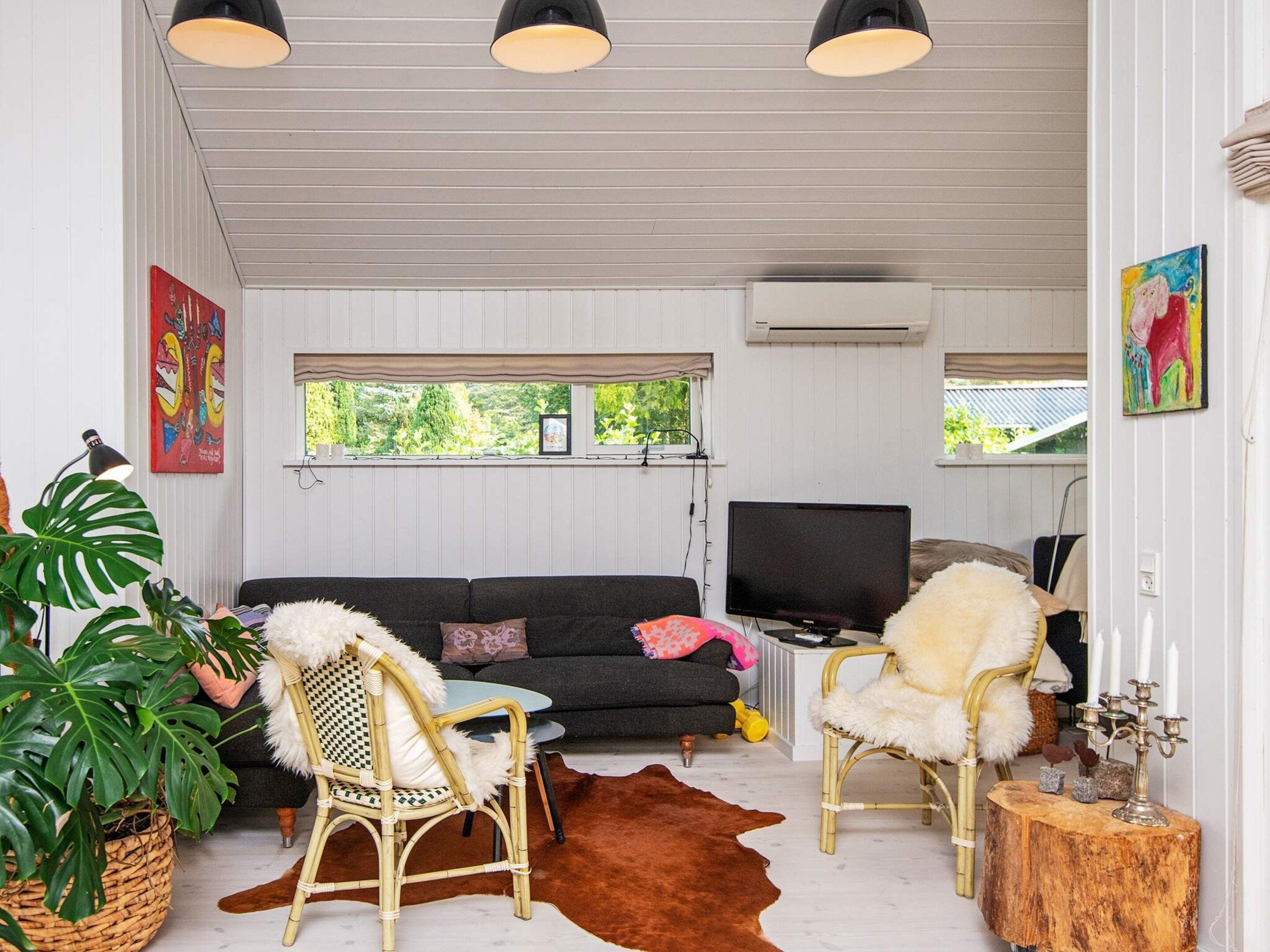 A cozy living room with a sofa, two chairs, a television, and a large plant.