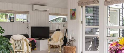 A room with a television, wicker chairs, a cowhide rug, and a large window.