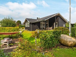 A modern house with a dark exterior, a well-maintained garden, and a large rock feature. - 4 Star Holiday Home in Malling (Malling)