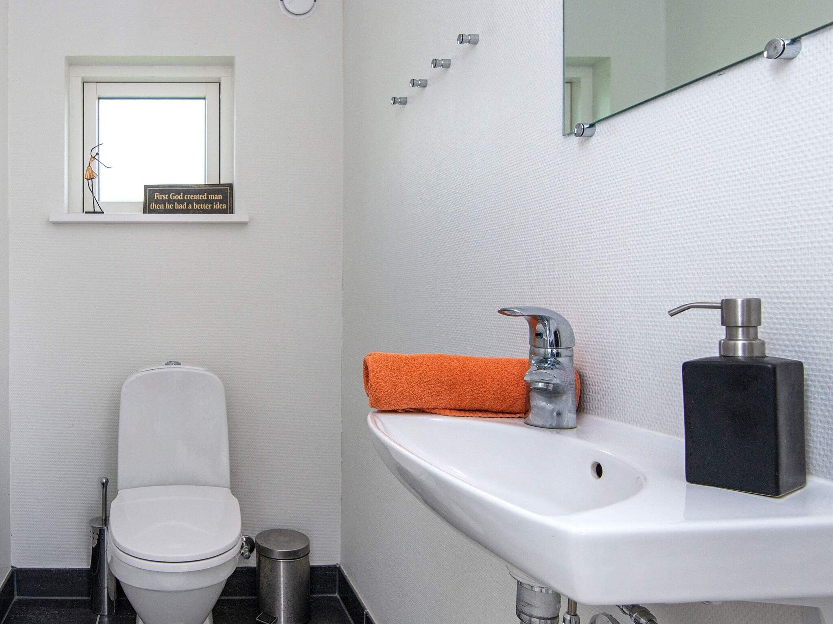 A bathroom with a toilet, a sink, and a window.