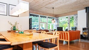 A modern interior with a wooden dining table, chairs, and a fireplace. - 4 Star Holiday Home in Juelsminde (Horsens)