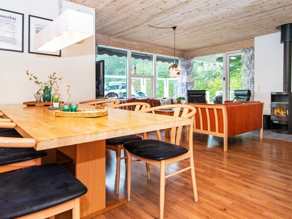 A modern interior with a wooden dining table, chairs, and a fireplace. - 4 Star Holiday Home in Juelsminde (Horsens)