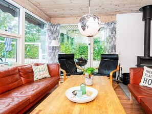 A cozy living room with a wooden table, leather sofas, a globe lamp, and a view of greenery outside. - 4 Star Holiday Home in Juelsminde (Horsens)