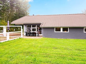 A single-story building with a tiled roof and a covered patio area with a table and chairs. - 4 Star Holiday Home in Juelsminde (Horsens)