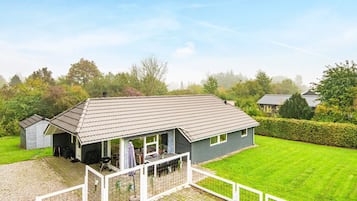 Una propiedad residencial con patio cercado, zona de estar al aire libre techada y césped bien cuidado.