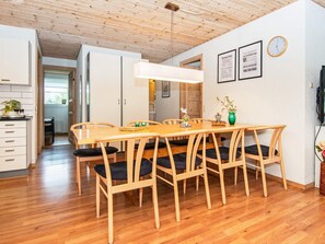 Un coin repas avec une table et des chaises en bois, un luminaire suspendu et une horloge au mur.