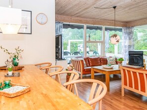 A cozy room with a wooden dining table, chairs, a sofa, and a television. - 4 Star Holiday Home in Juelsminde (Horsens)