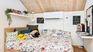 A cozy bedroom with a wooden ceiling, a floral bedspread, and a wall-mounted air conditioner. - 4 Star Holiday Home in Juelsminde (Horsens)