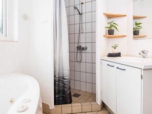 A bathroom with a shower, a sink, and a toilet. There are wooden shelves with plants and a towel. - 4 Star Holiday Home in Juelsminde (Horsens)