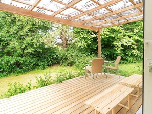 A wooden deck with a table and chairs, surrounded by lush greenery. - 4 Person Holiday Home in Graested (Graested)