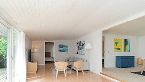 A modern living room with a sofa, two chairs, a TV, and artwork on the walls.
