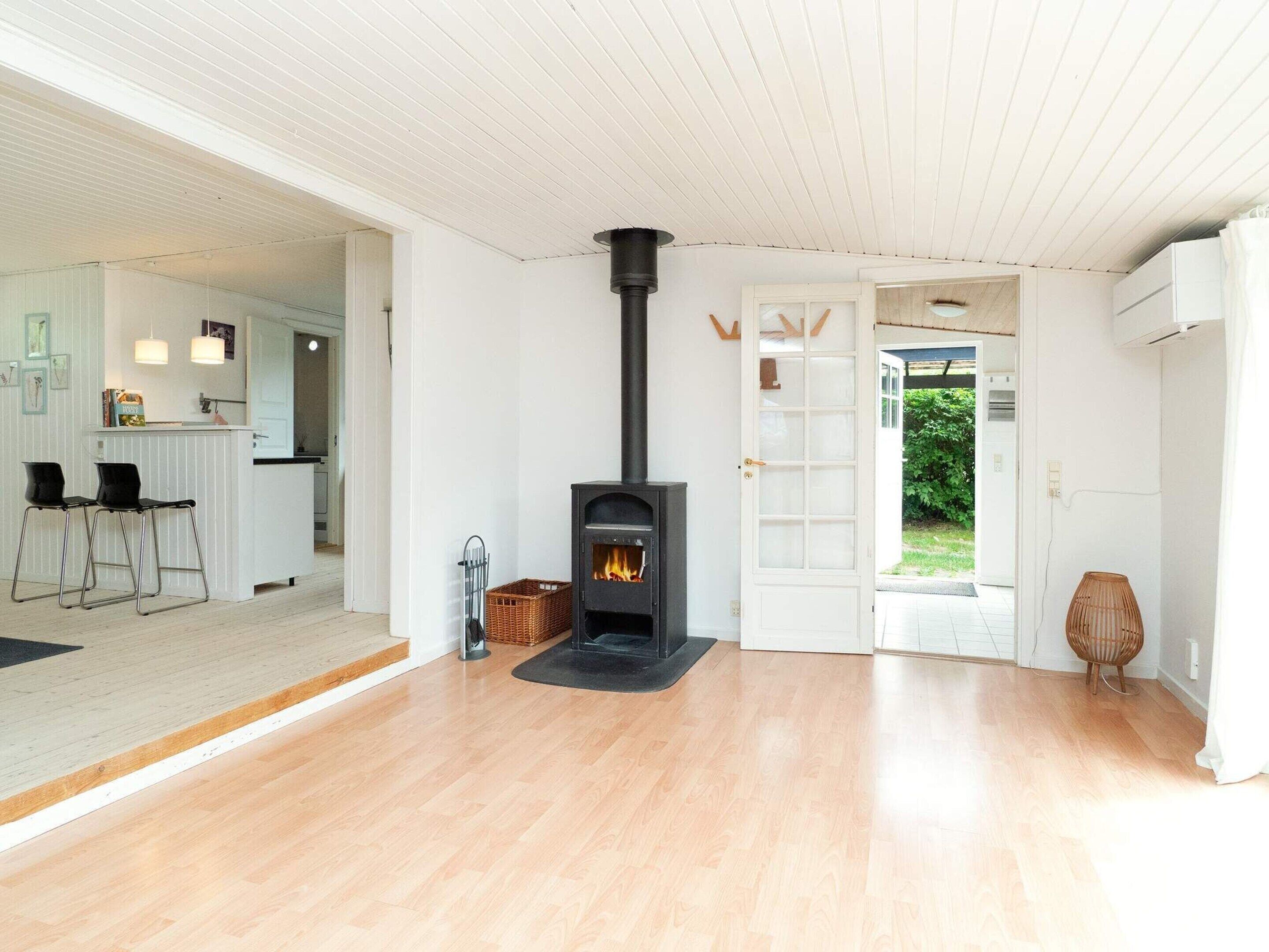 A modern interior with a wood-burning stove, a kitchen area, and a dining space with bar stools.