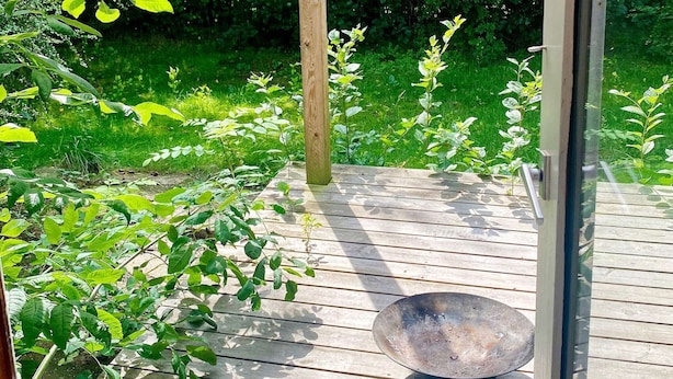 A wooden deck with a metal bowl and a glass door.