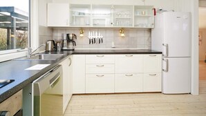 A modern kitchen with white cabinets, a black countertop, and a built-in dishwasher.