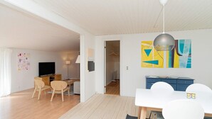 A modern living room with a dining area, wooden flooring, and a large abstract painting on the wall.