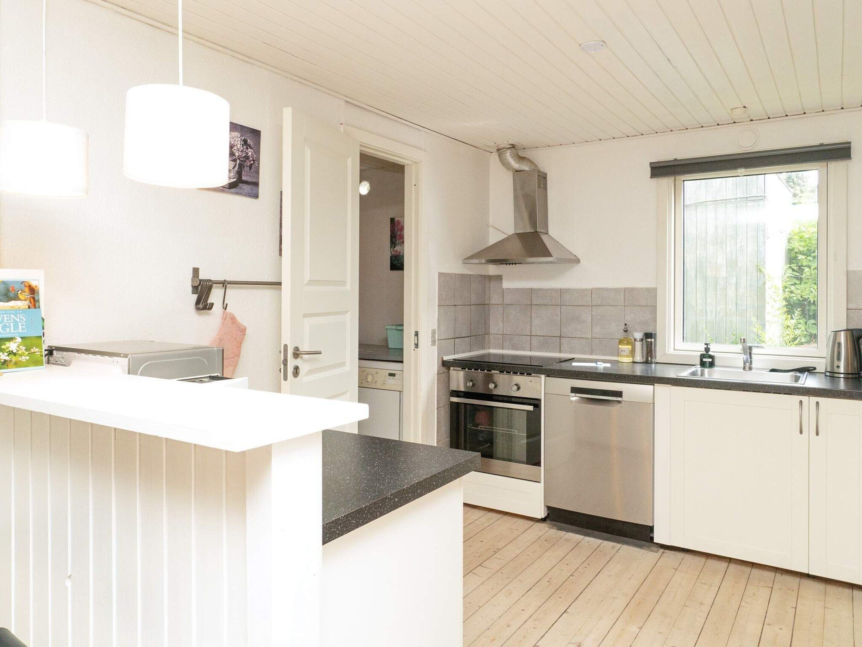 A modern kitchen with white cabinetry, a black countertop, stainless steel appliances, and a window providing natural light.