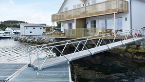 A waterfront property with a wooden deck, a metal staircase, and a white building with a balcony.